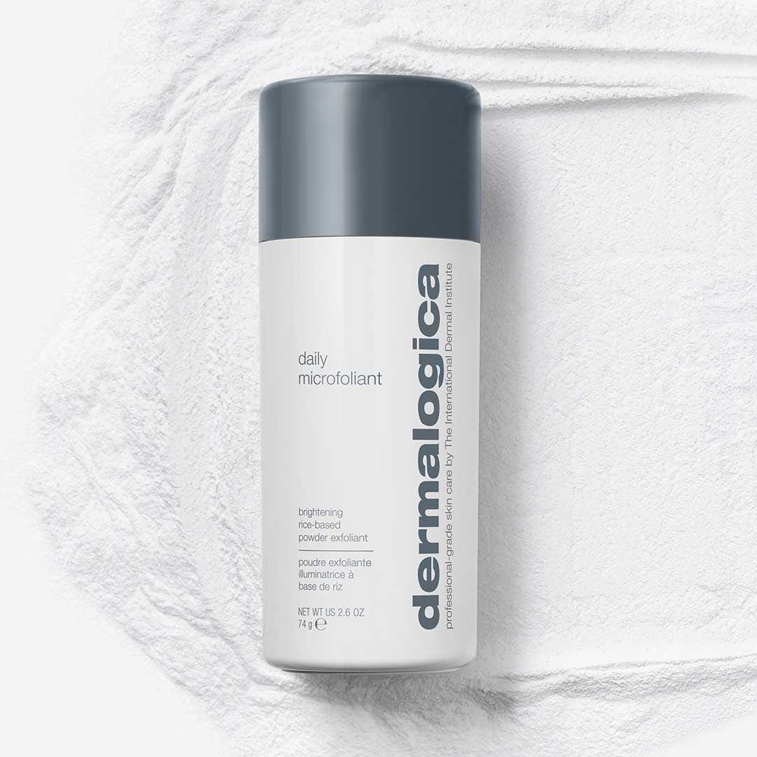 Ein Behälter mit Daily Microfoliant | Gesichtspeeling mit grauem Deckel steht auf einer strukturierten weißen Oberfläche und enthält einen einzigartigen Skin Brightening Complex zur Revitalisierung Ihres Teints.